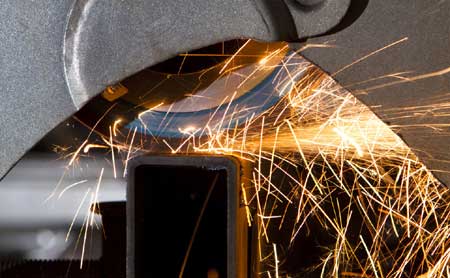 Cutting mild steel unequal box section on a cross cut saw in workshop in Wickford, Essex